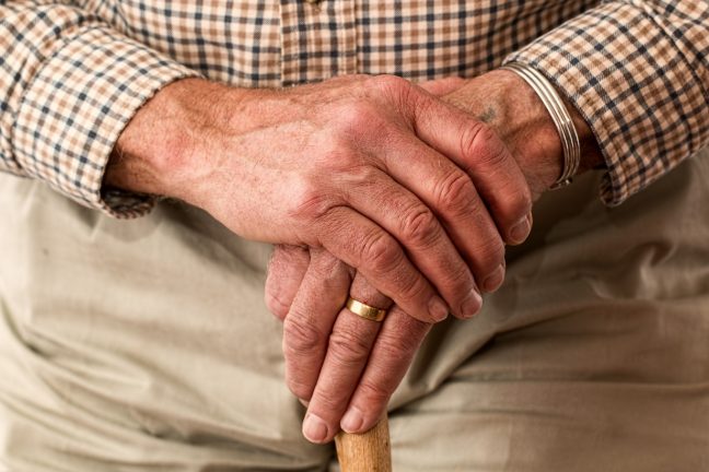 elderly man's hands resting on a walking stick