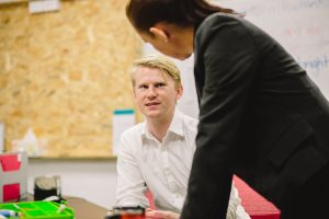 A seated student discusses a matter with their supervisor
