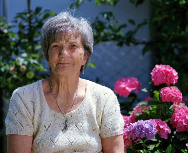senior woman sitting amongst flowers